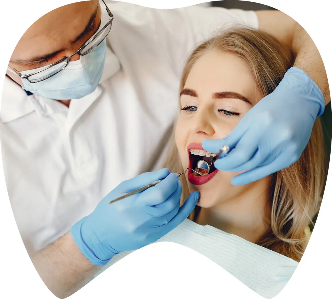 Dentist examining a patient’s mouth with dental tools, highlighting the veneer application process at La Clínica Dental in Mexico City.