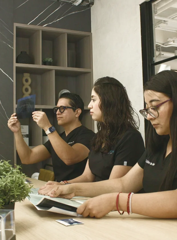 Equipo dental analizando radiografías y documentos en La Clínica Dental, enfocándose en la planificación de implantes guiados por computadora.